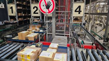 Kommissionierplätze an einem automatischen Tablarlager mit Kartons auf der Fördertechnik